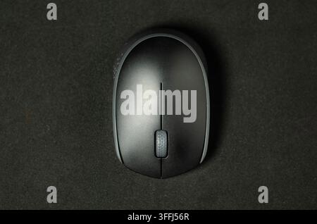 Moderne Maus ruht auf dunkler Oberfläche. Minimalistisches Design mit zentralem Scrollrad. Stockfoto