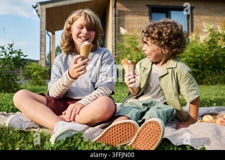 Zwei glückliche Kinder essen Eiscremekugeln während eines Sommerpicknicks im Freien Stockfoto