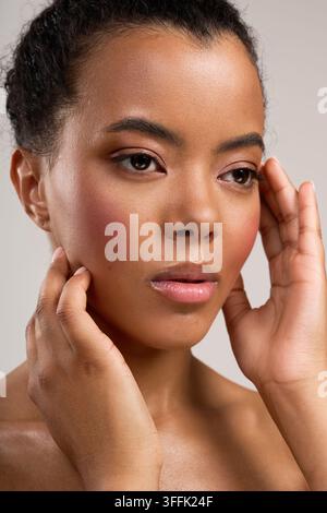 Eine junge Frau zeigt ihre Schönheit mit einer sanften Berührung und strahlt Selbstvertrauen aus. Stockfoto