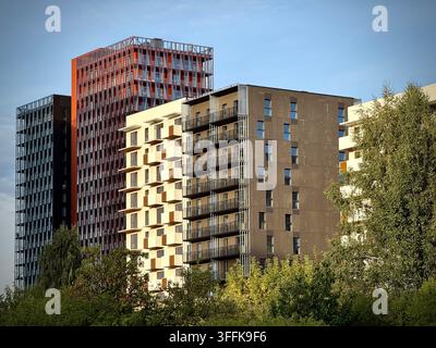 Niedrigwinkel-Foto von modernen Hochhaus-Büro- und Wohntürmen, die über grünen Bäumen in Vilnius, Litauen, aufragen. Stockfoto