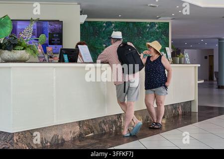 Las Palmas de Gran Canaria, Spanien – 9. September 2026: Seniorenpaar checkt an einem modernen Hotelrezeptionstresen ein, während ein Angestellter hinter der Theke steht. Stockfoto