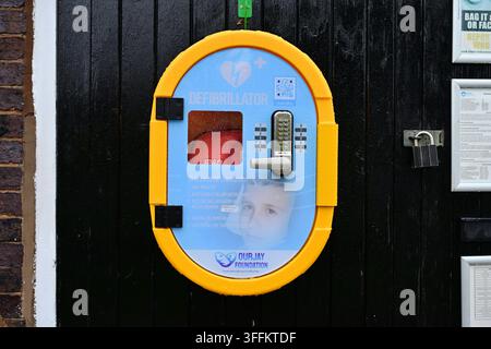 Öffentlicher Defibrillatorschrank an einer Holzwand in der Nähe der Straße montiert Stockfoto