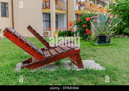 Zwei hölzerne Sonnenliegen stehen auf einem grünen Rasen im Garten Stockfoto