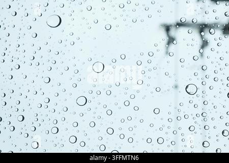 Viele Regentropfen auf der Windschutzscheibe des Autos am blauen bewölkten Himmel Stockfoto