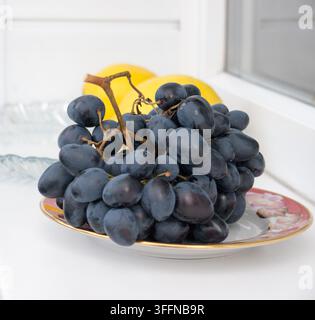 Schwarze Trauben und zwei Zitronen. Stockfoto