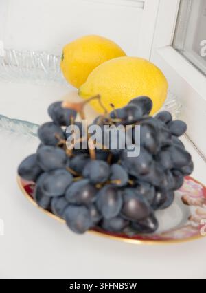 Schwarze Trauben und zwei Zitronen. Stockfoto
