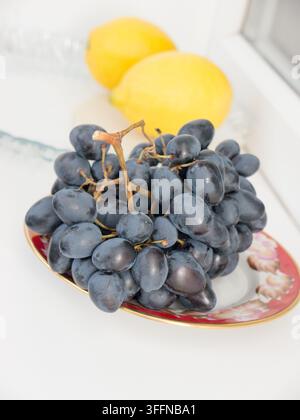 Schwarze Trauben und zwei Zitronen. Stockfoto