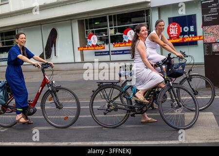 Graz, Österreich, 6. August 2026: Frauen fahren Fahrräder auf einer Stadtstraße in Graz. Drei Frauen mit Fahrrädern auf einer Stadtstraße in der Nähe des Jakominiplatzes in Graz Stockfoto