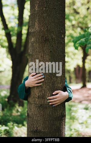 Eine Frau umarmt einen großen Baumstamm in einem sonnendurchfluteten Wald und drückt Verbindung mit der Natur, Umweltpflege, Gelassenheit und Wertschätzung für Waldgebiete aus Stockfoto