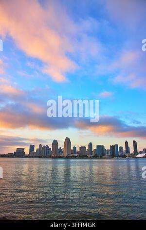Die Skyline von San Diego erhebt sich über der ruhigen Bucht, während Wolken in der Goldenen Stunde den Himmel mit warmen Tönen färben. Blick vom Coronado Park unterstreicht die Stadtlandschaft Stockfoto