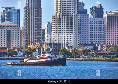Ein klassisches Schiff gleitet über die Bucht in San Diego, Kalifornien, während sich die Stadtsilhouette im Hintergrund erhebt. Der Uferbereich summt vor Aktivität, während moderne Bogen Stockfoto