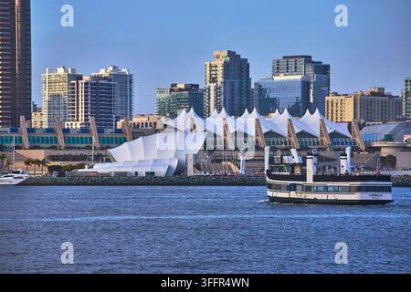 Ein klassisches Fährboot kreuzt die San-Diego-Bucht mit der Stadt Skyline und dem ikonischen Kongresszentrum im Hintergrund. Die Szene fängt das Lebendige ein Stockfoto