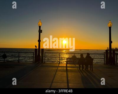Silhouetten von zwei Personen, die den Sonnenuntergang am Redondo Beach Pier, Kalifornien, USA beobachten Stockfoto