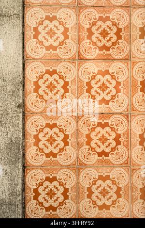 Nahaufnahme von orangefarbenen dekorativen Keramikfliesen mit einem sich wiederholenden Blumenmuster an einer Wand in Lissabon, Portugal. Stockfoto