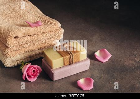 Bad und Spa Zubehör, Frottierwäsche und handgefertigten Lavendel und pflanzliche Seifen mit Rosenblättern dekoriert. Selektiver Fokus, kopieren Raum Stockfoto