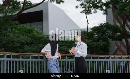 Asiatische Geschäftsfrauen führen ein Gespräch während der Kaffeepause im Freien Stockfoto