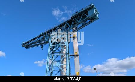 Die historische Titan-Clydebank-Kran wurde aus einem dramatischen Tiefwinkel aufgenommen, wobei sich seine massive Stahlkonstruktion über einen strahlend blauen Himmel erstreckt. Stockfoto