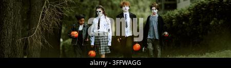 Kopfzeile einer vielfältigen Gruppe von Kindern in Kostümen, die draußen für Halloween spazieren gehen Stockfoto