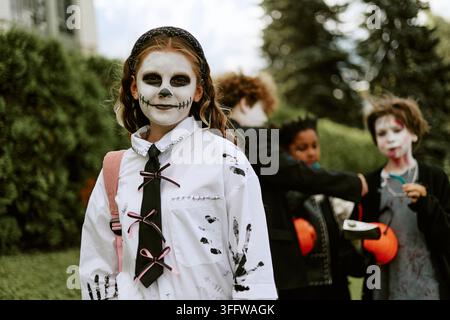 Porträt eines Mädchens mit Halloween-Make-up, das im Freien mit Freunden steht Stockfoto