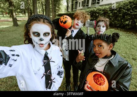 Porträt von vielfältigen Kindern in Halloween-Kostümen, die im Freien ein Selfie machen Stockfoto