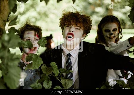 Porträt von Kindern in Halloween-Kostümen, die draußen Grimassen schneiden Stockfoto