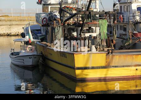 Bulgarischer Fischkutter Varna und ein kleines Boot, die Seite an Seite in einem ruhigen Hafen liegen, helle Reflexionen auf dem Wasser. Bulgarien, Byala, 7. September 2 Stockfoto
