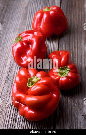 Rote Paprika auf einer rustikalen Holzoberfläche angeordnet. Biogemüse, minimales Food-Styling Stockfoto
