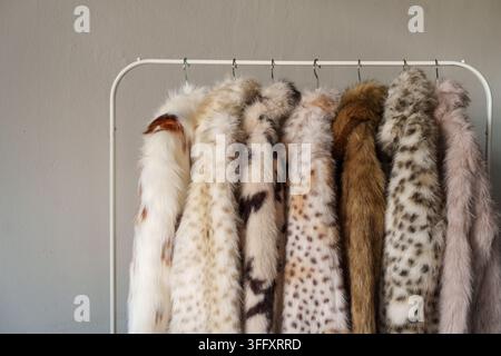 Kunstpelzmäntel hängen an einem Kleiderständer in einem neutralen Interieur Stockfoto