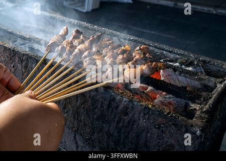 Koch grillt indonesisches Sate Klatak-Ziegenfleisch auf Metallspießen über flammendem Holzkohle, authentisches Straßenfood aus Yogyakarta. Stockfoto