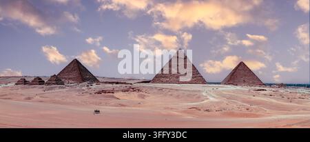 Luftbild der ikonischen Pyramiden von Gizeh, die aus der weiten Wüstenlandschaft unter einem weichen bewölkten Himmel aufragen Gizeh, Gouvernement Gizeh, Ägypten. Stockfoto