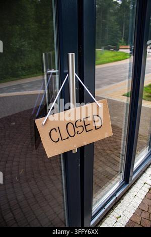 Schild „GESCHLOSSEN“ an der Willkommens­tür eines kleinen Ladens. Schließung eines lokalen Geschäfts. Inhaber sehen sich mit wirtschaftlichen Schwierigkeiten und Kundenverlust konfrontiert Stockfoto