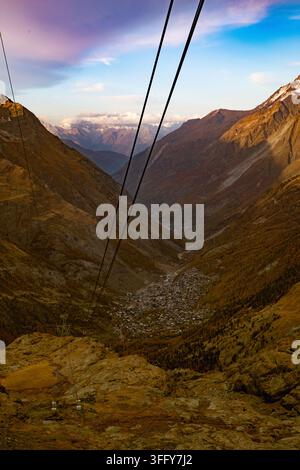 Luftaufnahme des Dorfes Zermatt, das in einem tiefen Tal liegt, umgeben von schroffen Herbstbergen und Seilbahnlinien in Zermatt, Wallis, Schweiz. Stockfoto