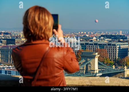 Ein Tourist macht ein Foto von der Budapester Panoramaansicht, einer wunderschönen Stadtsilhouette mit Blick auf die Stadt und die Donau mit der Kettenbrücke und wunderschön Stockfoto