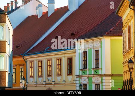 Lebendige historische Architektur in Budapest. Diese farbenfrohe Straßenansicht zeigt schöne mitteleuropäische Reihenhäuser mit auffälligen pastellfarbenen Fassaden an Stockfoto