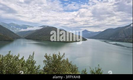 Türnisches Wasser des Zhinvali-Stausees, umgeben von grünen Bergen entlang der Georgischen Militärstraße Stockfoto