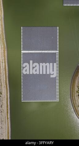 Luftaufnahme eines großen schwimmenden Solarfeldes, das auf einem ruhigen grünen Reservoir installiert ist, umgeben von natürlicher Landschaft in Erie, Colorado, Vereinigte Staaten. Stockfoto