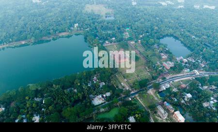 Luftbild der historischen Sixty Dome Moschee, umgeben von üppiger Vegetation und großen Wassertanks in Bagerhat, Khulna Division, Bangladesch. Stockfoto