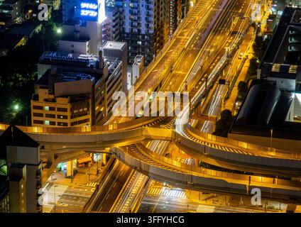 Luftbildnachtansicht einer kurvenreichen Autobahnkreuzung mit Lichtspuren, Kanto-Region, Tokio, Japan Stockfoto