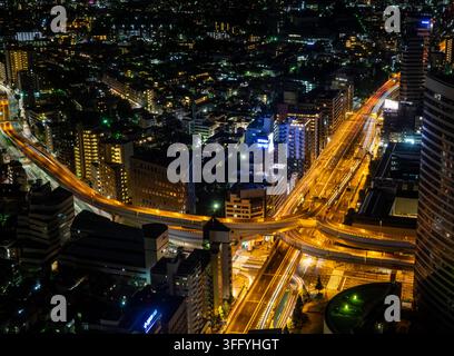 Luftbildnachtansicht von Tokyos Wolkenkratzern über einer geschwungenen Autobahnkreuzung, Kanto-Region, Tokio, Japan Stockfoto