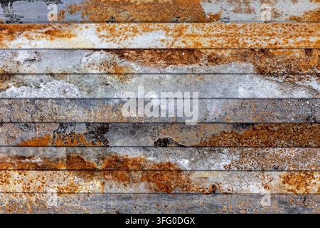 Verwitterte rostige Metallpaneele mit industrieller Patina. Nahaufnahme von verwitterten Metallstreifen mit grauen Oberflächen, orangefarbenem Rost, Korrosion und gesprenkelten Mustern Stockfoto