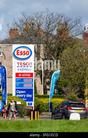 An einer Esso-Tankstelle mit einem Tesco Express zeigt ein Preistotem die Kraftstoffpreise, während ein Auto vorbeifährt. Southport, UK. Stockfoto