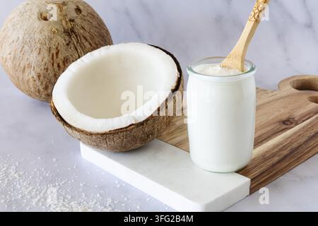 Kokosnuss und Kokosjoghurt, ganz und halbiert, mit frischem Fleisch Stockfoto