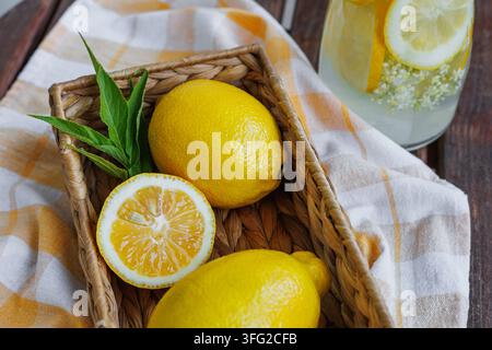Frische Zitronen und Minzblätter in einem Korb mit Limonadenhintergrund Stockfoto