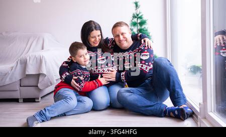 Glückliche Familie mit einer schwangeren Frau, die festliche Pullover trägt und lächelt Stockfoto
