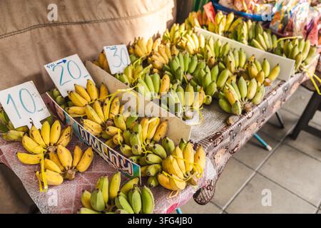 Farbenfrohes Bananendisplay mit handgeschriebenen Preiskarten auf dem Markt in Bangkok Stockfoto