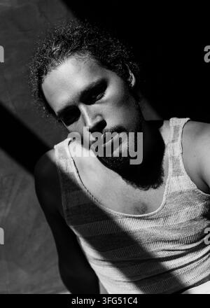 Schwarz-Weiß-Nahaufnahme-Porträt eines Mannes in einem Tanktop unter dramatischer Seitenbeleuchtung mit intensivem Blick Stockfoto