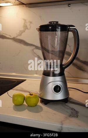 Vertikal stilierte Komposition eines Arbeitsplattenmixers mit frischen grünen Äpfeln in einer modernen Küchenzeile, geeignet für gesunde Koch- und Smoothie-Konzeption Stockfoto