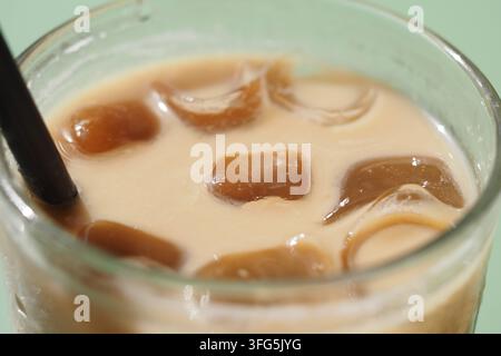 Kaffee mit Eis in einem klaren Glas auf einem grünen Tisch Stockfoto