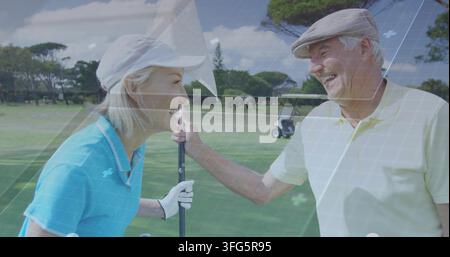 Lächelnde reife Frau und Senior, die einen Flaggenpfahl auf dem Golfgrün handhaben, tragen Poloshirts und Visier Stockfoto