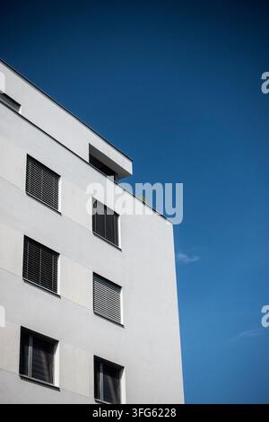 Niedrigwinkelaufnahme eines modernen weißen Wohnhauses mit Fensterläden vor einem tiefblauen Himmel und sauberem Kopierraum Stockfoto